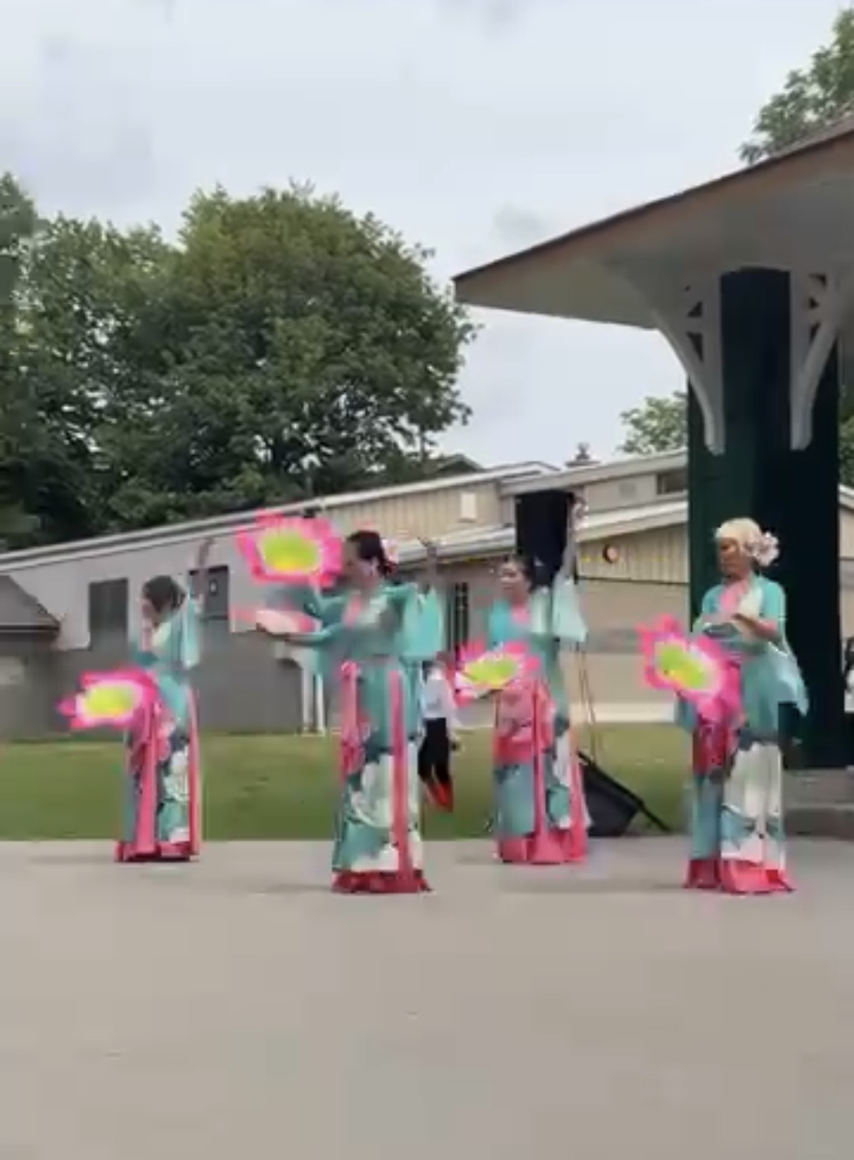 Fan dance performance in teal and pink costumes